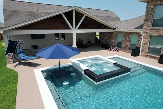 Custom pool with covered patio and outdoor living space by Pools of Houston