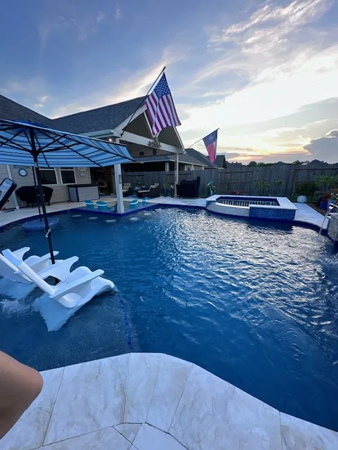 Freeform pool with spa at sunset with American flag