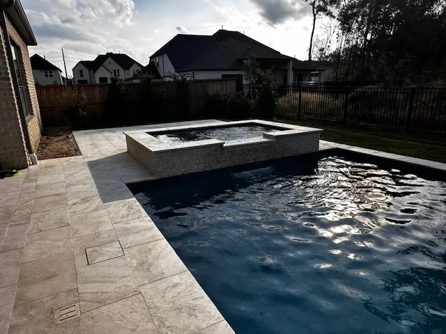 Pool with raised stone spa and travertine deck