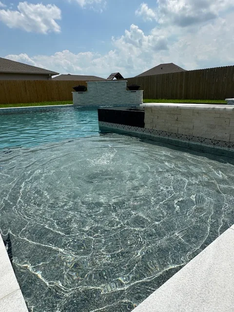 Beach entry pool with raised water feature wall